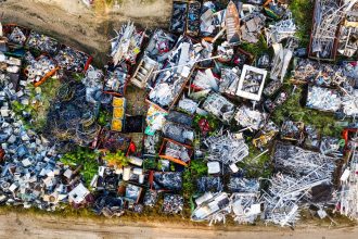 Vista aérea de um depósito de sucata com grandes pilhas de materiais metálicos.