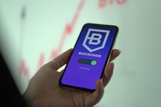 Mão segurando um smartphone com a tela de uma carteira de criptomoedas baseada em blockchain.
