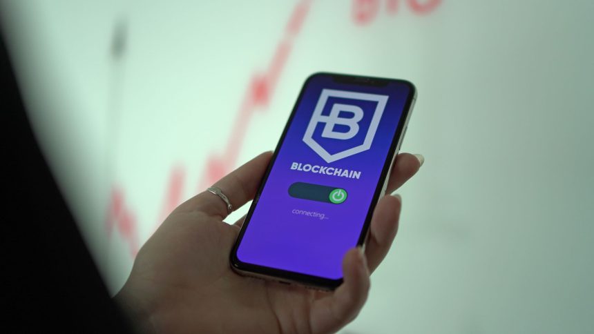 Mão segurando um smartphone com a tela de uma carteira de criptomoedas baseada em blockchain.