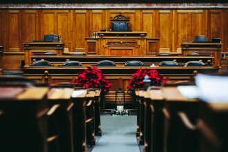 Interior amplo de uma sala de tribunal vazia, com bancos e mobiliário de madeira.