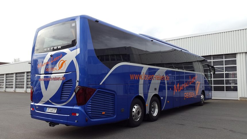 Ônibus rodoviário azul estacionado ao ar livre sob um céu parcialmente nublado.